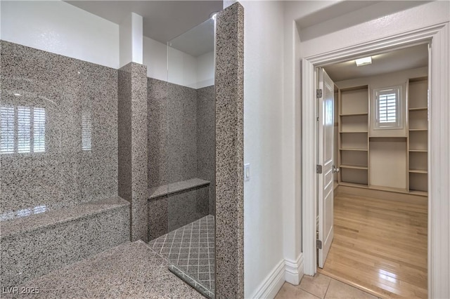 full bathroom featuring tile patterned floors, baseboards, and tiled shower