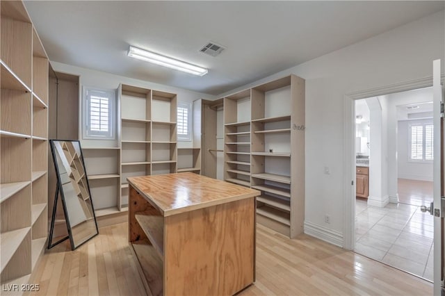 spacious closet with arched walkways, visible vents, and light wood-style floors