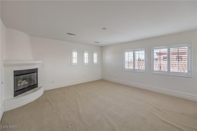 unfurnished living room with a large fireplace, baseboards, visible vents, and light carpet