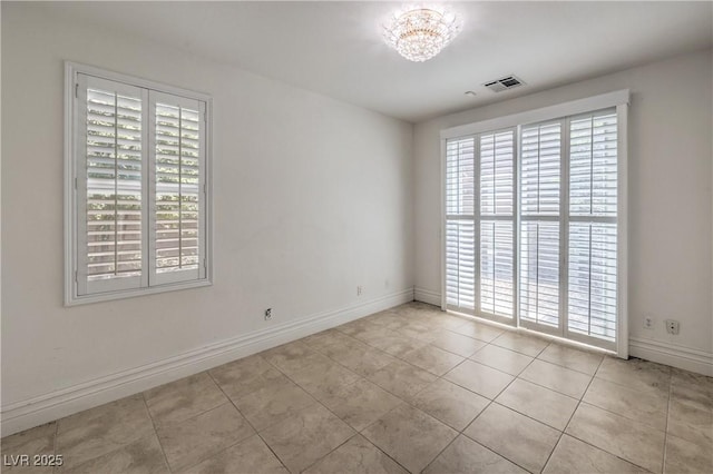 spare room with tile patterned floors, visible vents, a chandelier, and plenty of natural light