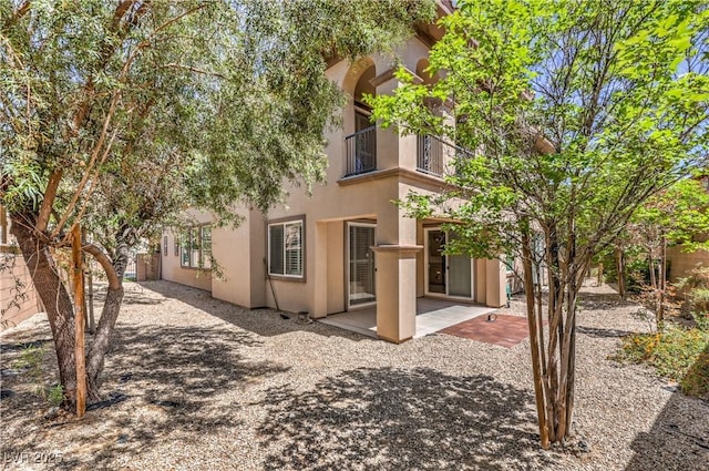 back of property featuring fence, stucco siding, a patio area, and a balcony
