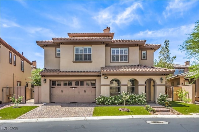 mediterranean / spanish home with stucco siding, decorative driveway, a gate, and a garage