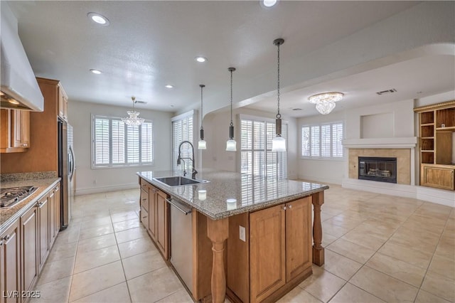 kitchen featuring a sink, visible vents, stainless steel appliances, wall chimney exhaust hood, and a notable chandelier