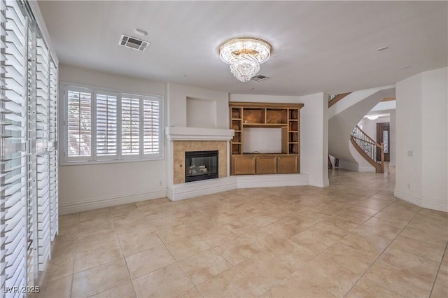 unfurnished living room featuring light tile patterned floors, visible vents, a chandelier, arched walkways, and a tile fireplace