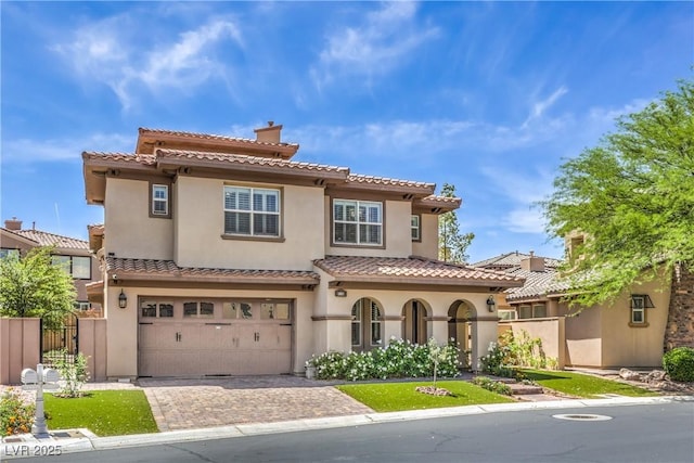 mediterranean / spanish-style house featuring a garage, driveway, a tiled roof, stucco siding, and fence