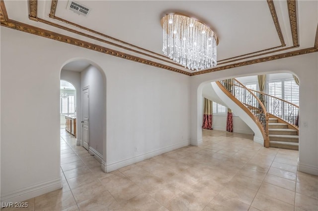 interior space with arched walkways, stairs, baseboards, visible vents, and a notable chandelier