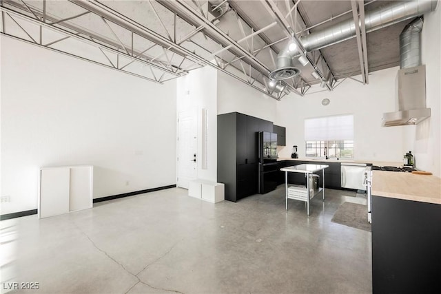 kitchen with white dishwasher, a high ceiling, range hood, light countertops, and dark cabinetry