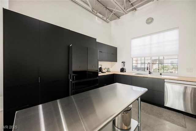kitchen featuring modern cabinets, stainless steel dishwasher, a sink, light countertops, and dark cabinetry