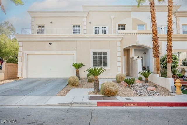 view of front facade featuring concrete driveway, an attached garage, a balcony, and stucco siding