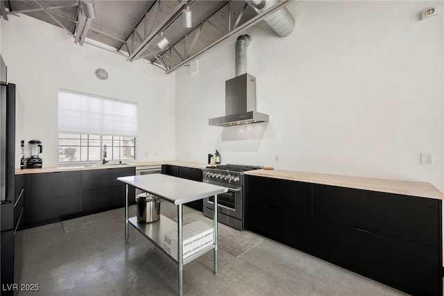 kitchen featuring high end stainless steel range, modern cabinets, light countertops, wall chimney exhaust hood, and dark cabinets