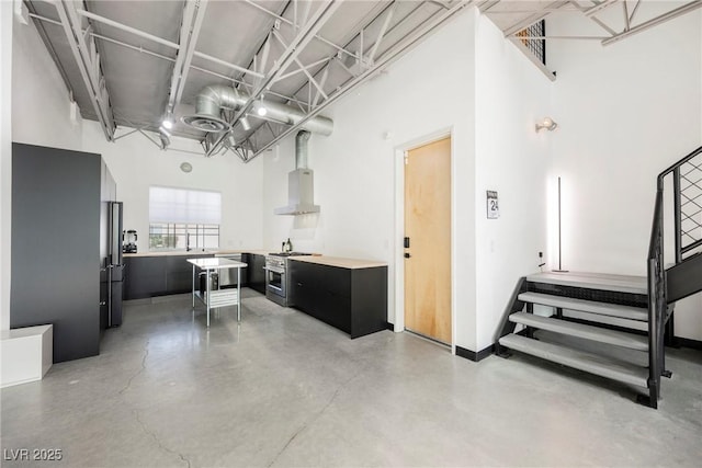 interior space featuring dark cabinets, extractor fan, concrete floors, freestanding refrigerator, and high end stainless steel range oven