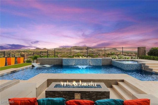 103 Reflection Cove Dr, Henderson, NV 89011 - pool at dusk with a fire pit, a pool with connected hot tub, and a fenced backyard