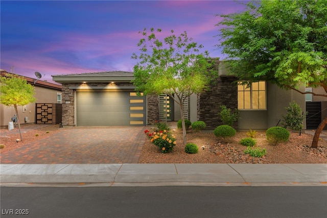103 Reflection Cove Dr, Henderson, NV 89011 - view of front of house featuring stucco siding, an attached garage, decorative driveway, and stone siding