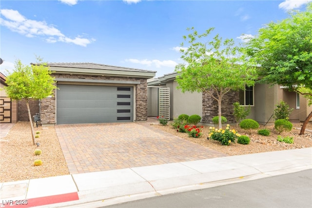 103 Reflection Cove Dr, Henderson, NV 89011 - view of front of home with stone siding, a garage, decorative driveway, and stucco siding