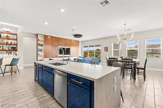 103 Reflection Cove Dr, Henderson, NV 89011 - kitchen with visible vents, stainless steel dishwasher, blue cabinets, a sink, and a kitchen island with sink