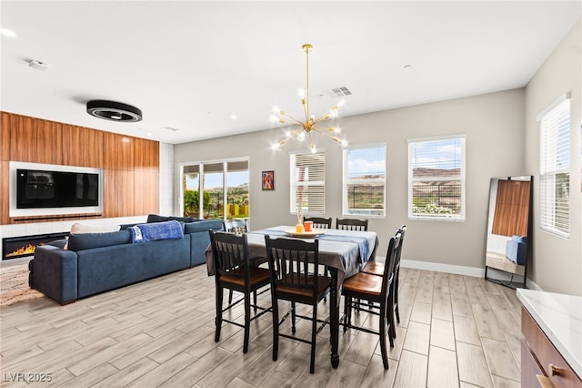 103 Reflection Cove Dr, Henderson, NV 89011 - dining room with a warm lit fireplace, light wood-style flooring, baseboards, a notable chandelier, and visible vents