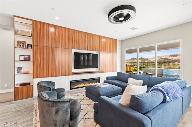 103 Reflection Cove Dr, Henderson, NV 89011 - living room featuring a glass covered fireplace, light wood-type flooring, visible vents, and baseboards