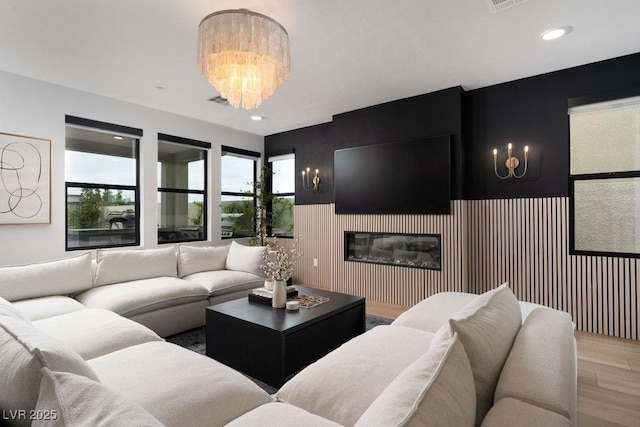 living room featuring a chandelier, a glass covered fireplace, wood finished floors, and recessed lighting