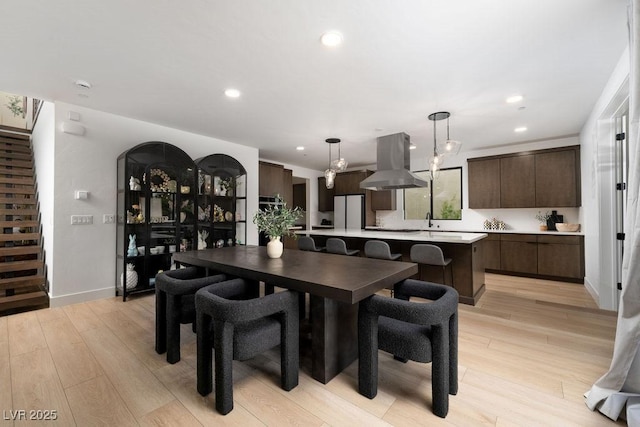 dining space with recessed lighting, light wood-style floors, baseboards, and stairs