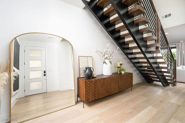 interior space featuring arched walkways, light wood-style floors, visible vents, and stairs