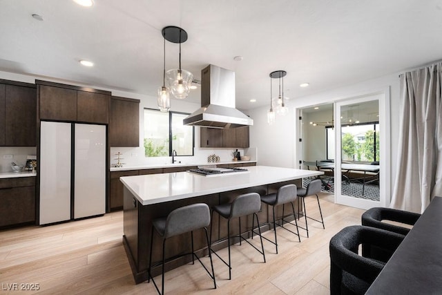 kitchen featuring light countertops, freestanding refrigerator, island exhaust hood, and a healthy amount of sunlight