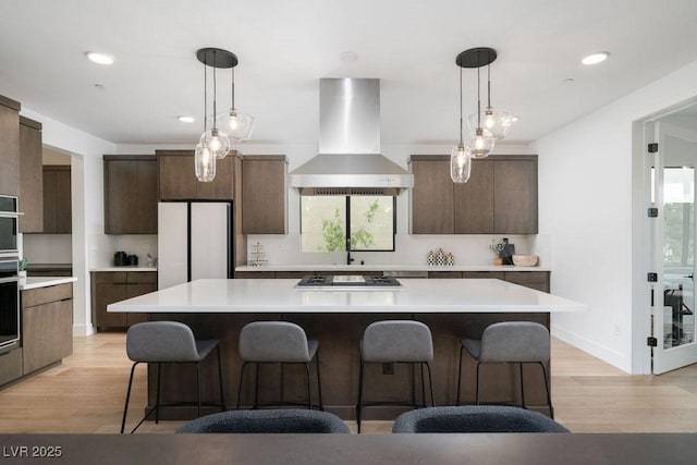 kitchen featuring recessed lighting, light wood-style floors, and wall chimney exhaust hood
