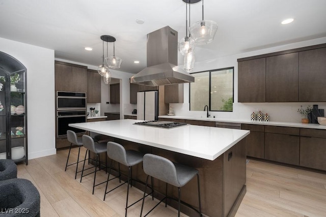 kitchen featuring island exhaust hood, dark brown cabinets, gas cooktop, freestanding refrigerator, and dobule oven black