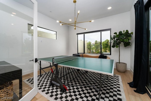 recreation room featuring recessed lighting, light wood finished floors, baseboards, and an inviting chandelier