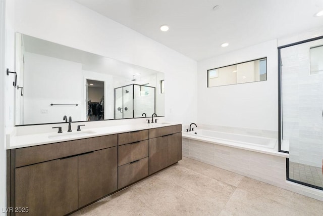 bathroom with a garden tub, a sink, a shower stall, and double vanity