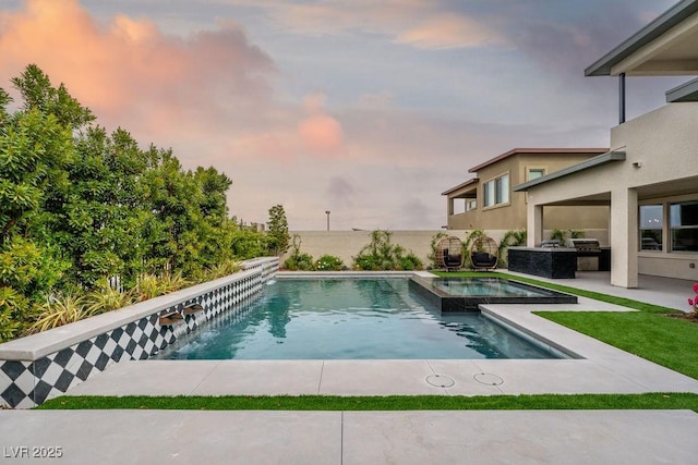 view of pool featuring exterior kitchen, fence, a patio, a pool with connected hot tub, and area for grilling
