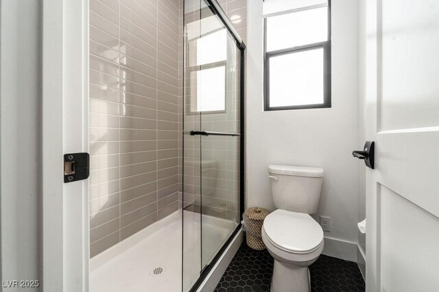 full bath with tile patterned flooring, baseboards, toilet, and a stall shower