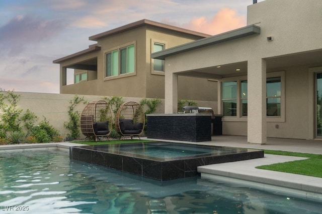 pool at dusk with an outdoor pool, a patio, and an in ground hot tub