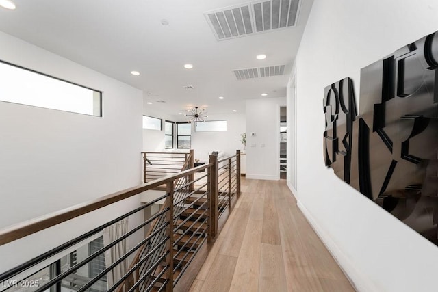 hallway featuring recessed lighting, visible vents, light wood finished floors, and an upstairs landing