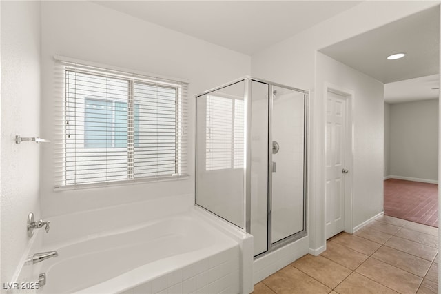 bathroom featuring a bath, baseboards, tile patterned flooring, and a shower stall