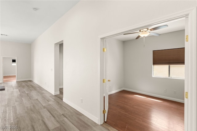 spare room featuring wood finished floors, a ceiling fan, and baseboards
