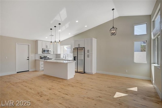 kitchen with light wood-type flooring, recessed lighting, light countertops, a kitchen island, and appliances with stainless steel finishes