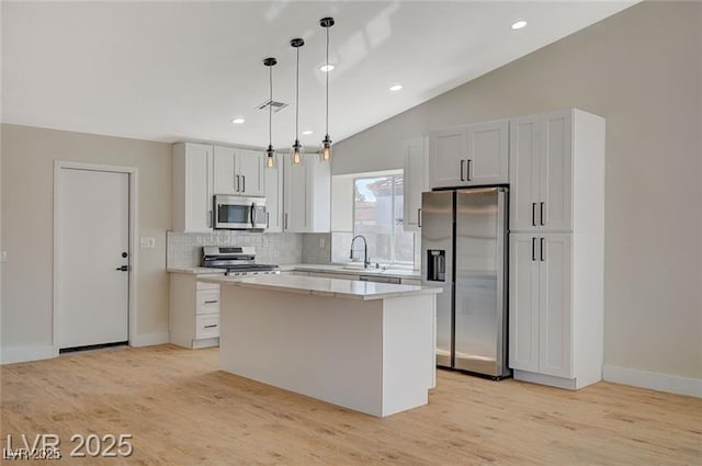 kitchen featuring a sink, tasteful backsplash, visible vents, a kitchen island, and appliances with stainless steel finishes