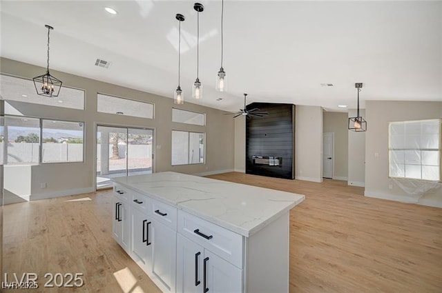 kitchen featuring visible vents, light wood-style floors, a center island, open floor plan, and ceiling fan with notable chandelier