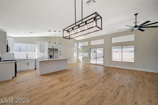 kitchen featuring visible vents, appliances with stainless steel finishes, open floor plan, and a sink