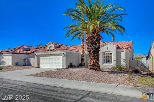 mediterranean / spanish home with an attached garage, concrete driveway, a tiled roof, and stucco siding