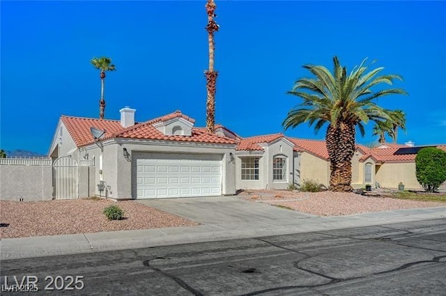 mediterranean / spanish-style house with stucco siding, an attached garage, a tile roof, and concrete driveway