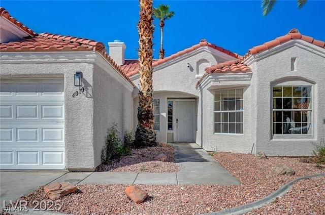view of front facade featuring an attached garage, a tiled roof, and stucco siding