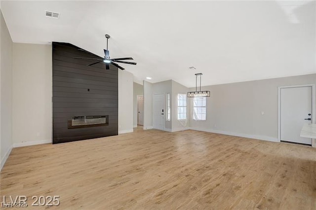 unfurnished living room with vaulted ceiling, ceiling fan with notable chandelier, a fireplace, baseboards, and visible vents