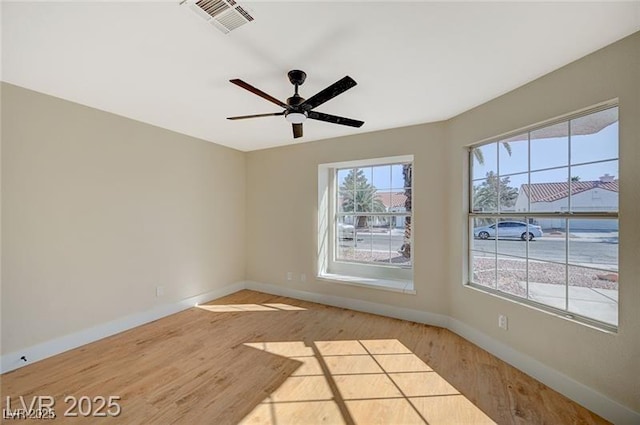 spare room featuring visible vents, baseboards, a ceiling fan, and wood finished floors