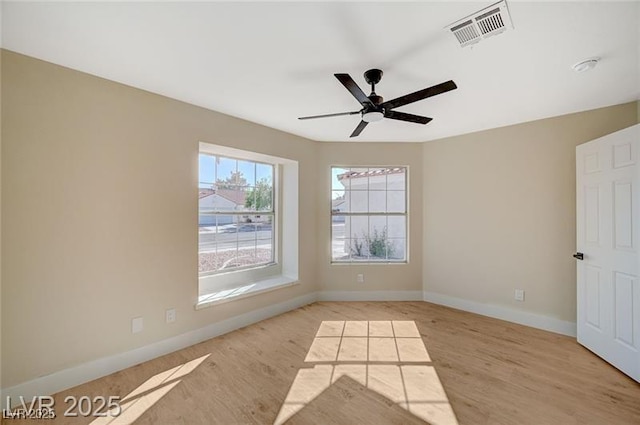 empty room featuring visible vents, light wood finished floors, baseboards, and ceiling fan