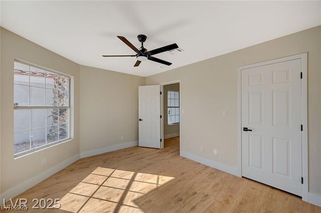 unfurnished bedroom featuring light wood finished floors, baseboards, and multiple windows