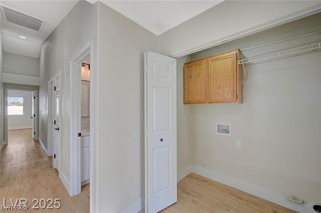 washroom featuring light wood-type flooring, baseboards, visible vents, washer hookup, and cabinet space