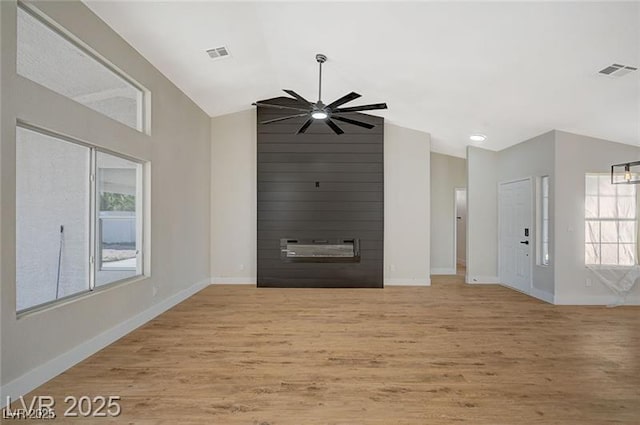 unfurnished living room featuring lofted ceiling, visible vents, ceiling fan, and plenty of natural light
