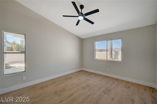 spare room with ceiling fan, vaulted ceiling, wood finished floors, and baseboards