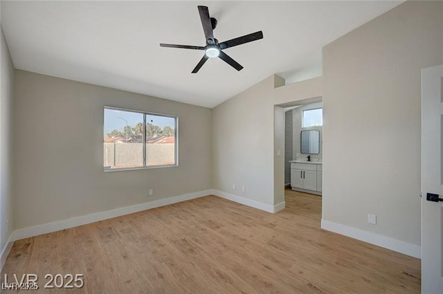 spare room featuring lofted ceiling, a healthy amount of sunlight, ceiling fan, and light wood-type flooring